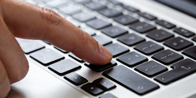 特写一只手指在笔记本电脑键盘上敲击快捷键，背景虚化