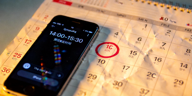 一个日历的特写，某个日期上有一个标记，旁边是显示预定时间的手机界面